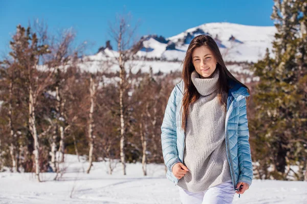 Retrato de uma jovem bela mulher morena com olhos azuis e sardas no rosto no inverno paisagem de montanha nevada. Menina bonita no inverno ao ar livre . — Fotografia de Stock