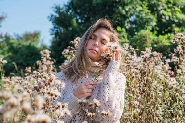 Ritratto di giovane donna felice in maglione e con agrimonia secca. donna soffiando su asciutto bur — Foto Stock