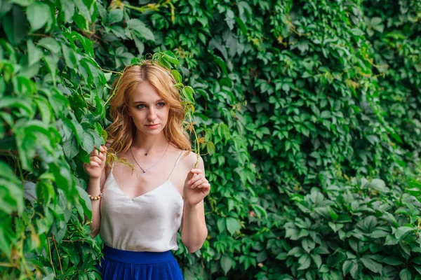 Retrato de una joven mujer hermosa, de pie junto a la pared de hojas de uva silvestre . — Foto de Stock