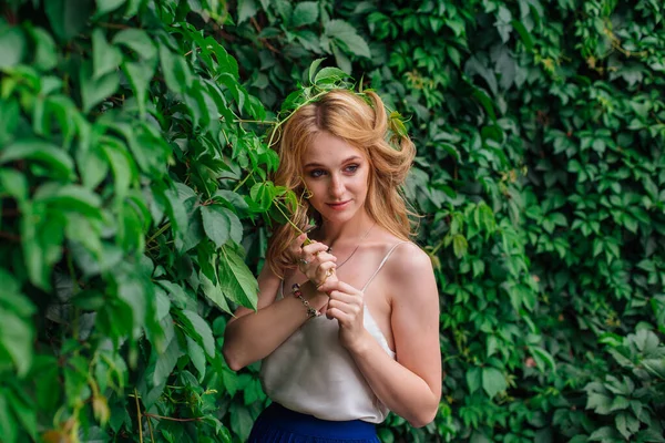 Portrait of a young beautiful woman, standing next to the wall of wild grape leaves. — Stock Photo, Image