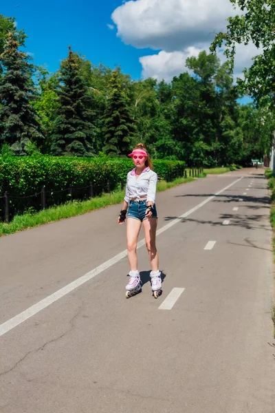 Portret van een emotioneel meisje in een roze GLB Visor en beschermende handschoenen voor inline skates en skateboarden rijden op inline skates op de weg. — Stockfoto