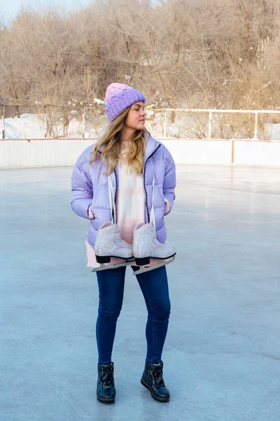 Belle jeune femme avec des patins à glace suspendus sur le cou sur la patinoire . — Photo