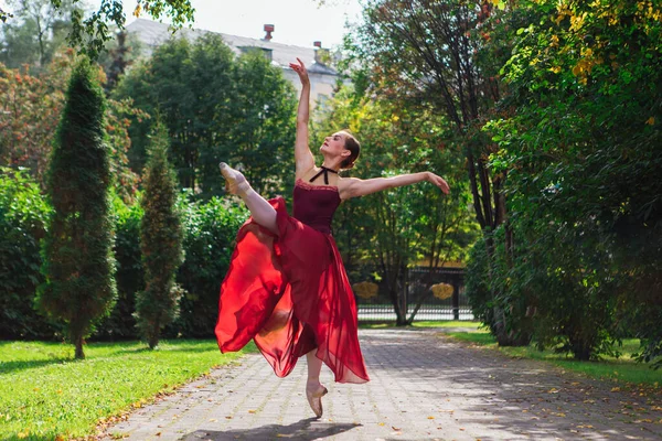 Bailarina de mujer en vestido de ballet rojo bailando en zapatos puntiagudos en el parque de otoño . —  Fotos de Stock