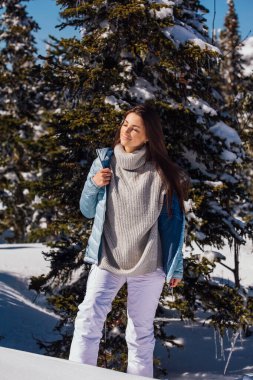 Kışın karlı dağ manzarasında mavi gözlü ve yüzünde çiller olan güzel esmer bir kadının portresi. Kışın açık havada güzel bir kız.