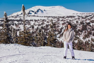 Kışın karlı dağ manzarasında mavi gözlü ve yüzünde çiller olan güzel esmer bir kadının portresi. Kışın açık havada güzel bir kız.