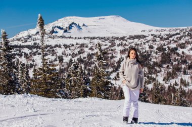 Kışın karlı dağ manzarasında mavi gözlü ve yüzünde çiller olan güzel esmer bir kadının portresi. Kışın açık havada güzel bir kız.
