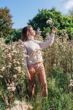 Kuru tarlada çıplak ayakla yürüyen süveter ve iç çamaşırlı mutlu genç bir kadın.