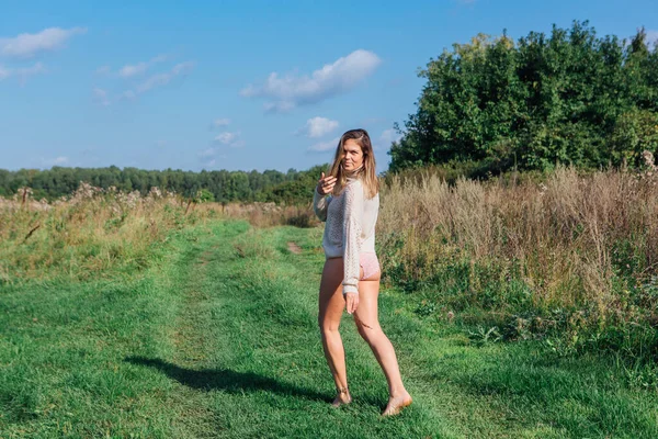 Glückliche junge schöne Frau, die barfuß in einem grünen Feld geht — Stockfoto