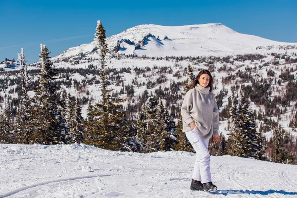 Porträt einer jungen schönen brünetten Frau mit blauen Augen und Sommersprossen im Gesicht in der winterlich verschneiten Berglandschaft. schöne Mädchen im Winter im Freien. — Stockfoto