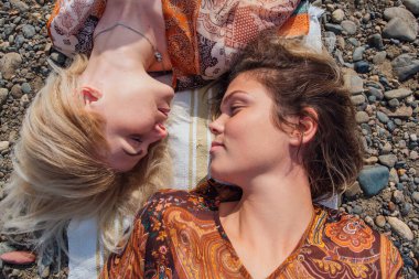 İki güzel genç kadın esmer ve sarışın kafa kafaya yatıyorlar..