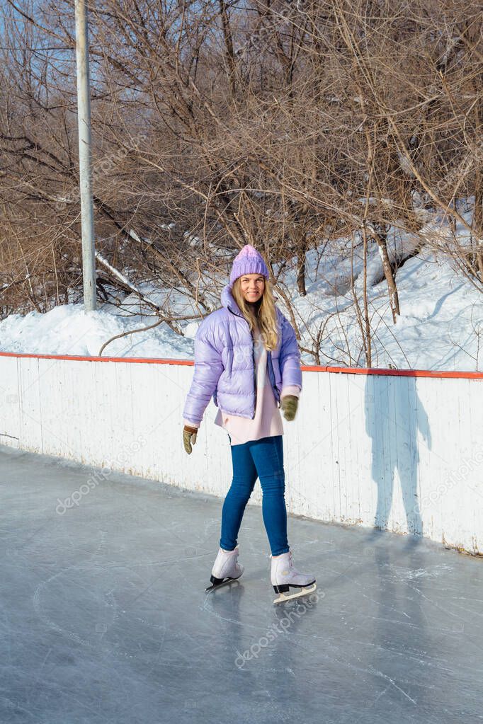 Lovely young woman with riding ice skates on the ice rink.