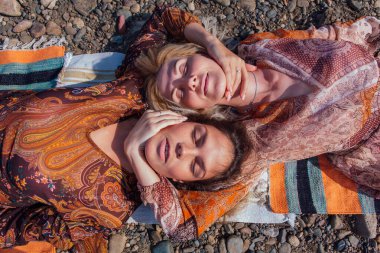 İki güzel genç kadın esmer ve sarışın kafa kafaya yatıyorlar..