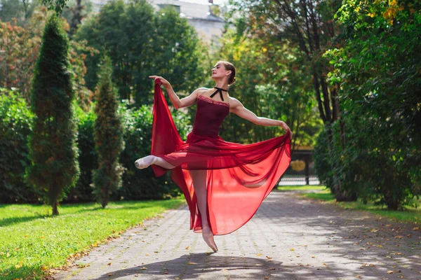 Bailarina de mujer en vestido de ballet rojo bailando en zapatos puntiagudos en el parque de otoño . —  Fotos de Stock