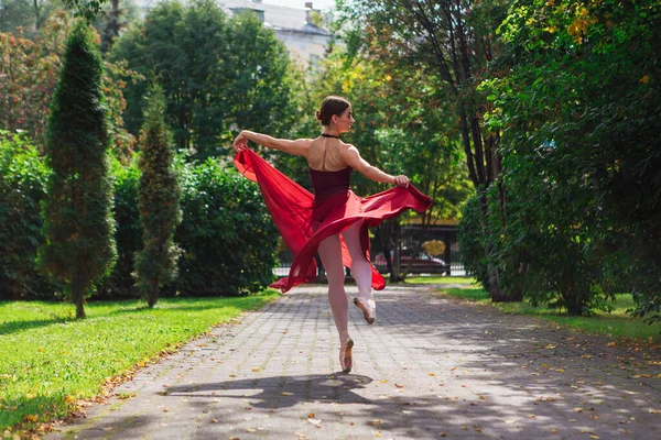 Γυναίκα μπαλαρίνα σε κόκκινο φόρεμα μπαλέτου χορό σε pointe παπούτσια στο πάρκο φθινόπωρο. — Φωτογραφία Αρχείου