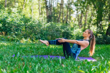 Beyaz bir kadın yaz kenti parkında yoga egzersizleri yapıyor..