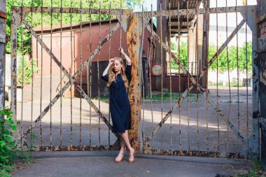 Eski paslı kapının yanında duran uzun sarı saçlı, moda görünümlü kadın. Genç kadın modern portre.