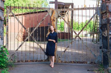 Eski paslı kapının yanında duran uzun sarı saçlı, moda görünümlü kadın. Genç kadın modern portre.