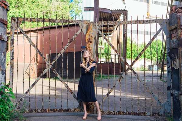 Eski paslı kapının yanında duran uzun sarı saçlı, moda görünümlü kadın. Genç kadın modern portre.