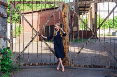 Eski paslı kapının yanında duran uzun sarı saçlı, moda görünümlü kadın. Genç kadın modern portre.