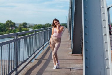 Gün batımında nehrin üzerindeki eski paslı nakliye köprüsünde poz veren genç ve güzel bir kadının ılık yaz portresi..