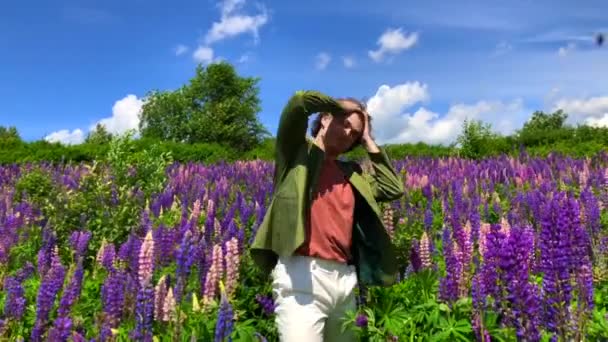 Hombre alto y guapo bailando en el campo de flores de altramuz — Vídeos de Stock