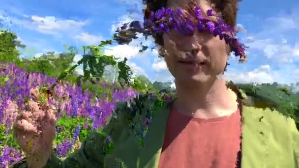 Tall handsome man standing on lupine flowers field with eyes closed by a flower of lupine — Stock Video