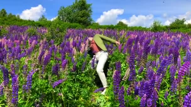 Високий красивий чоловік танцює на полі квітів люпину — стокове відео