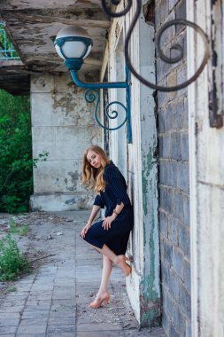 Süslü antika bir feneri olan eski bir binanın yanında duran güzel sarışın kadın.