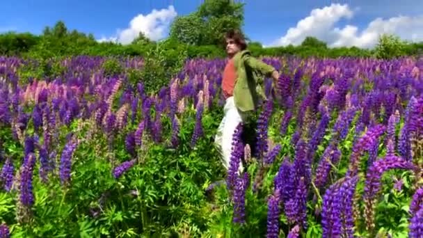 Tall handsome man dancing on lupine flowers field — Stock Video