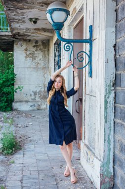 Süslü antika bir feneri olan eski bir binanın yanında duran güzel sarışın kadın.