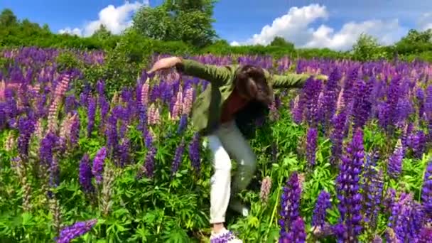 Lång stilig man dansar på lupine blommor fält — Stockvideo