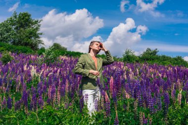 Lupin çiçeklerinin üzerinde duran uzun boylu yakışıklı adam.