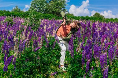 Uzun boylu, yakışıklı bir adam Lupin çiçeklerinin arasında dans ediyor.