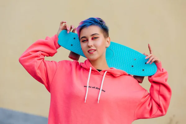 Stijlvolle jonge vrouw met skateboard op haar schouders. Jeugdconcept. — Stockfoto