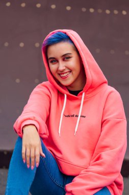 Pembe kapüşonlu kısa saçlı ve burunlu genç kız.