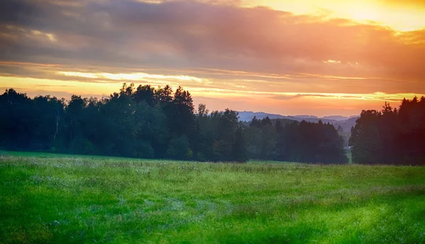 Pôr do sol nas terras altas. Campos, florestas e céu beatiful na hora do verão . — Fotografia de Stock