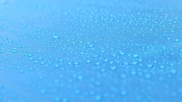 Druppels water op een blauw oppervlak. Prachtige macro foto van water bellen of dauw. — Stockfoto