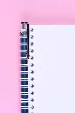 Kitabın boş Not kağıt kalem ile pembe bir arka plan üzerinde üstten görünüm