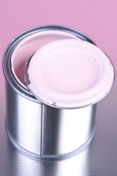 Opened can with pink paint on metallic background close-up
