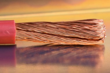 Closeup stripped copper cable on metallic table with blurred background clipart