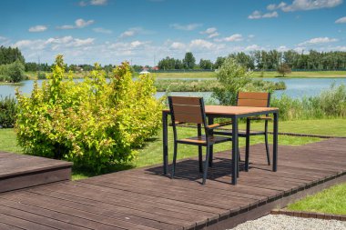 Gölün kıyısındaki parkta boş sandalyeler ve masa