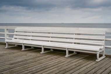 Deniz kıyısındaki tahta kaldırımda boş bir bank.