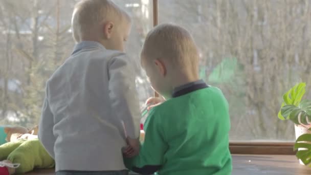Dois irmãos estão olhando para o peitoril da janela na época do Natal — Vídeo de Stock