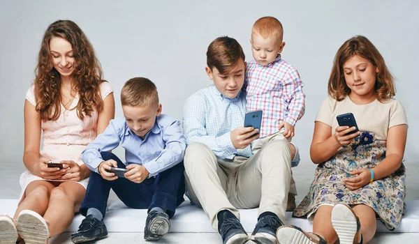 A los niños se centran en jugar teléfonos inteligentes . —  Fotos de Stock