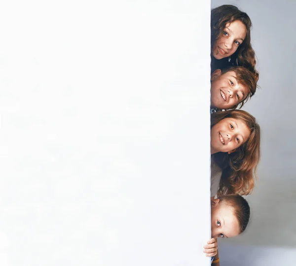 Чотири дитини, що тримають великий рекламний щит, з'являються з боку щита . — стокове фото