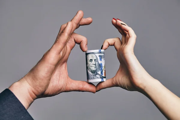 Un rotolo di dollari con il cuore fatto di due mani. amore denaro concetto — Foto Stock