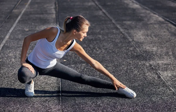 Junge läuferisch fitte Frau, die sich vor den Übungen im Freien ausstreckt. Athletische weibliche Dehnung nach dem Training draußen. Sport und Menschen-Konzept. — Stockfoto