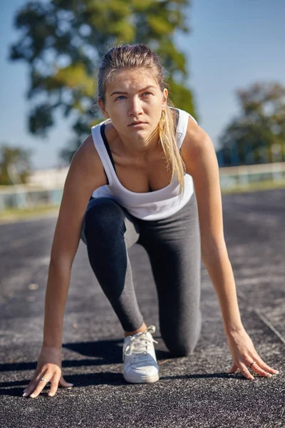 Eine junge Läuferin bereitet sich auf einen Lauf auf der Strecke vor — Stockfoto