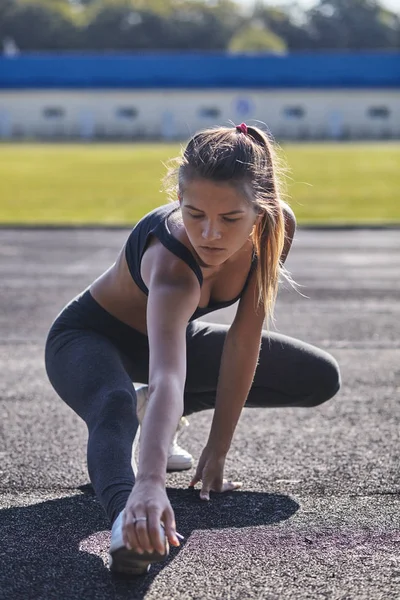 Junge läuferisch fitte Frau, die sich vor den Übungen im Freien ausstreckt. Athletische weibliche Dehnung nach dem Training draußen. Sport und Menschen-Konzept. — Stockfoto