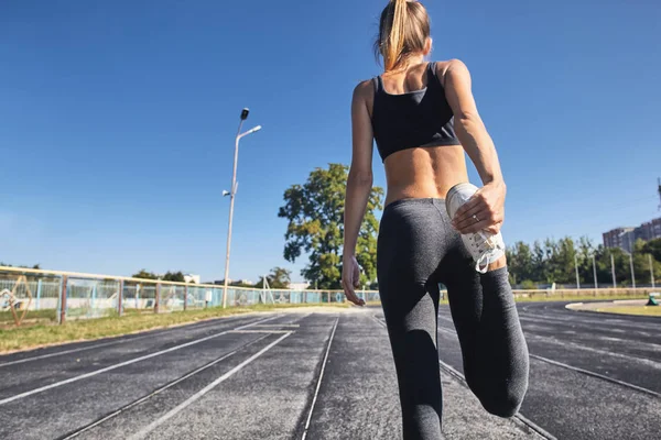 Junge läuferisch fitte Frau, die sich vor den Übungen im Freien ausstreckt. Athletische weibliche Dehnung nach dem Training draußen. Sport und Menschen-Konzept. — Stockfoto
